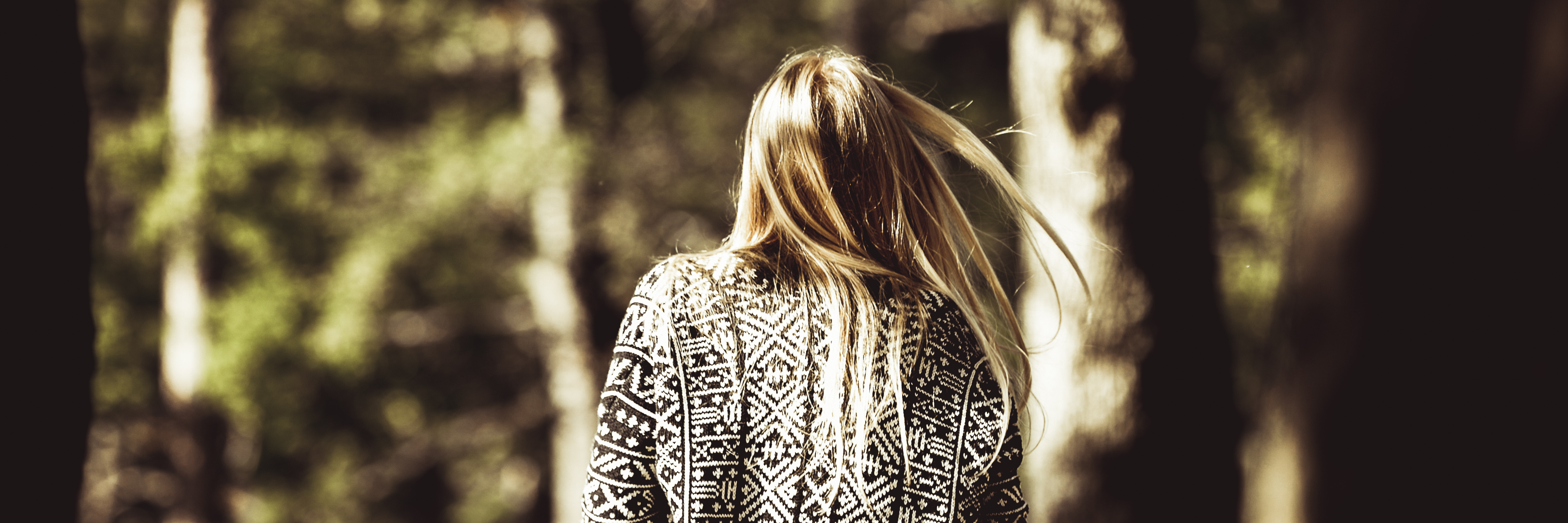 young woman walking in park rear shot muted colours