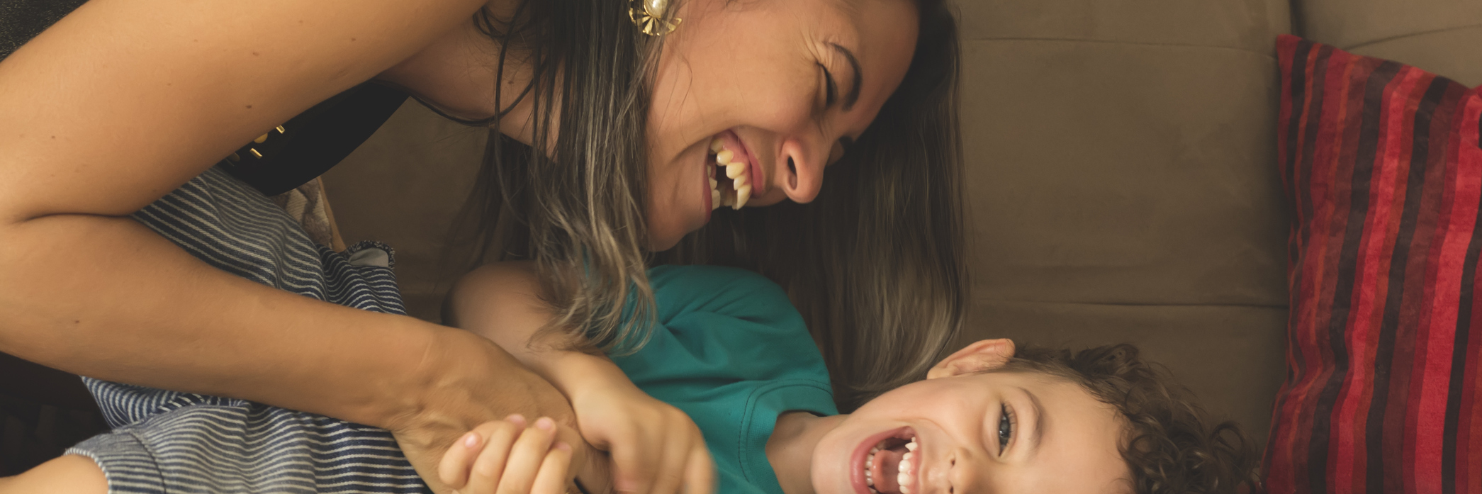 Mother Reminded by Rare Disease Family She Is Not Defined by Illness mother tickling and playing with young son on the couch