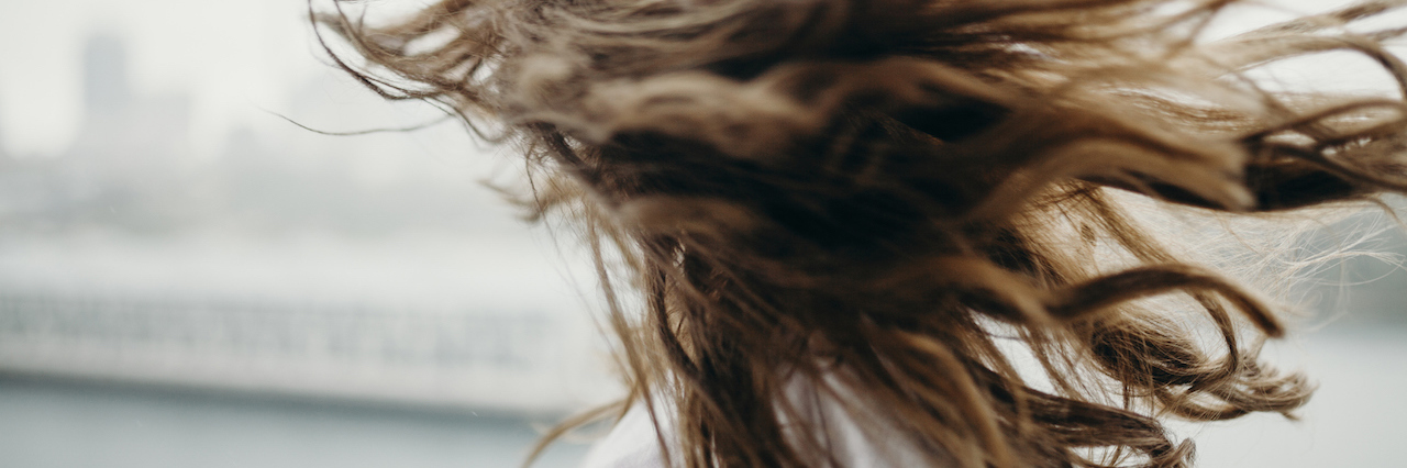 What It's Like Days After a Panic Attack A woman flipping her hair, looking out into a city covered in clouds