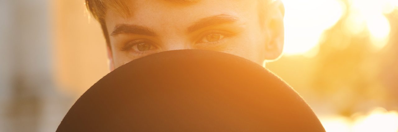 A woman hiding her face behind a hat