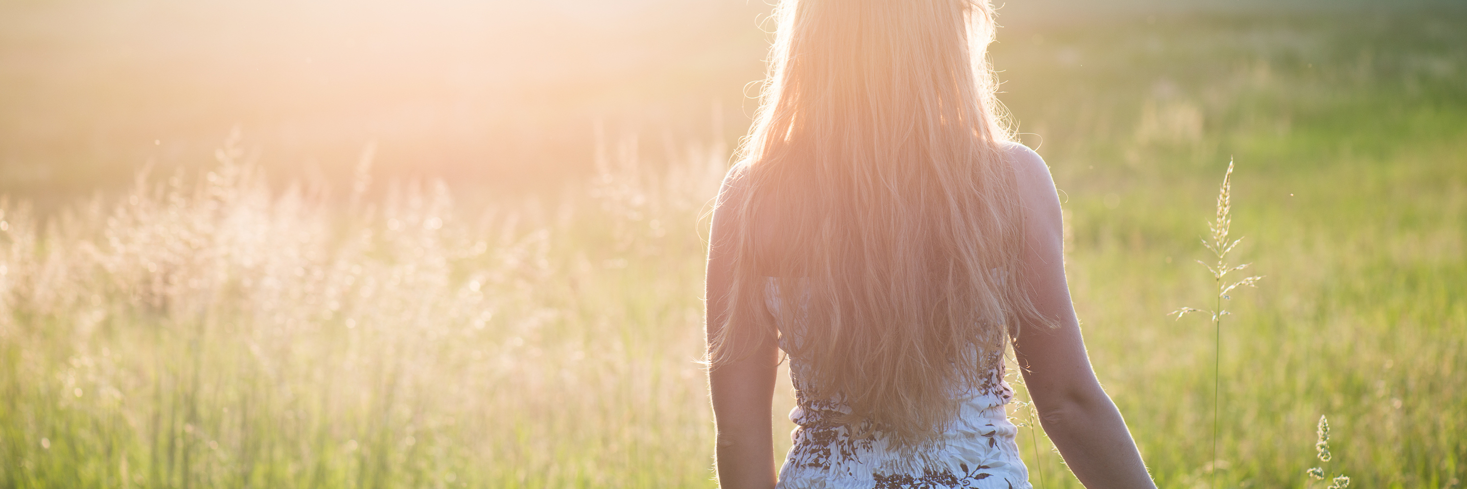 young woman walking in sunset in field