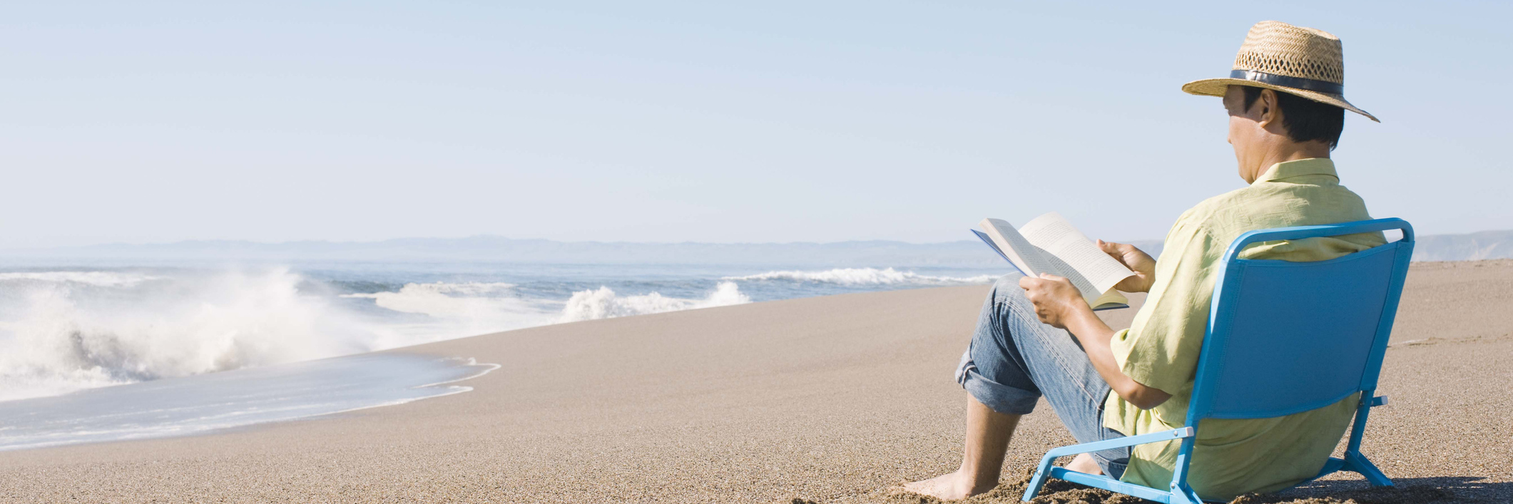 man reading a book on the beach