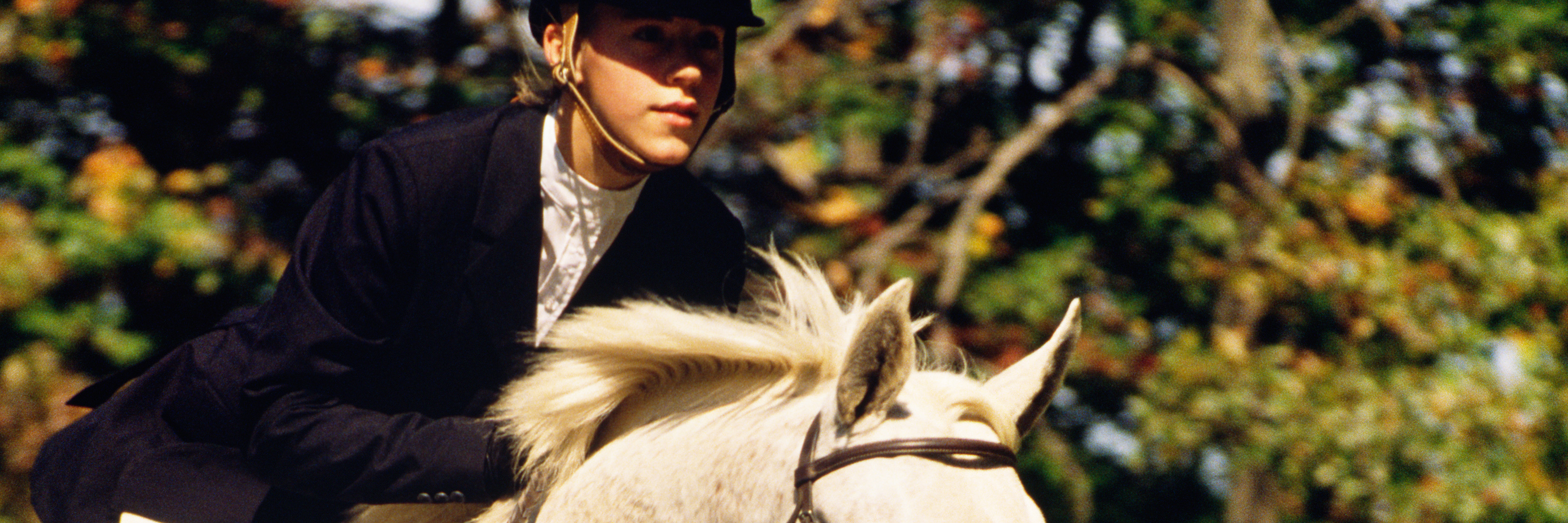 What a Difficult Horse Riding Exercise Taught Me About My Anxiety young woman on white horse jumping over obstacle