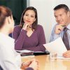 two business colleagues conducting interview with young woman