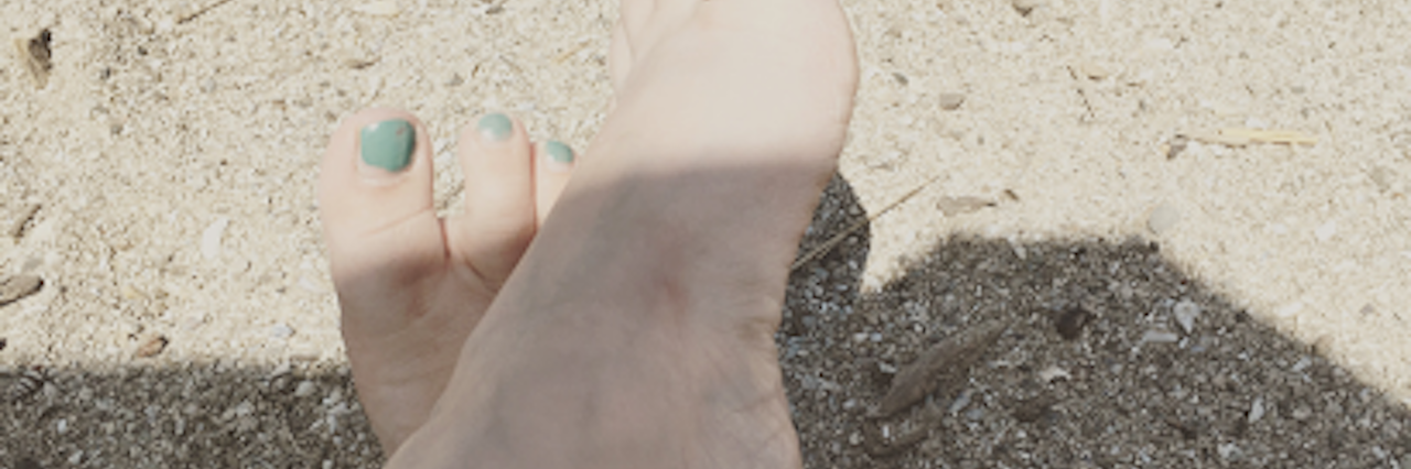 woman's feet in the shade with just her toes peeking out into the sun