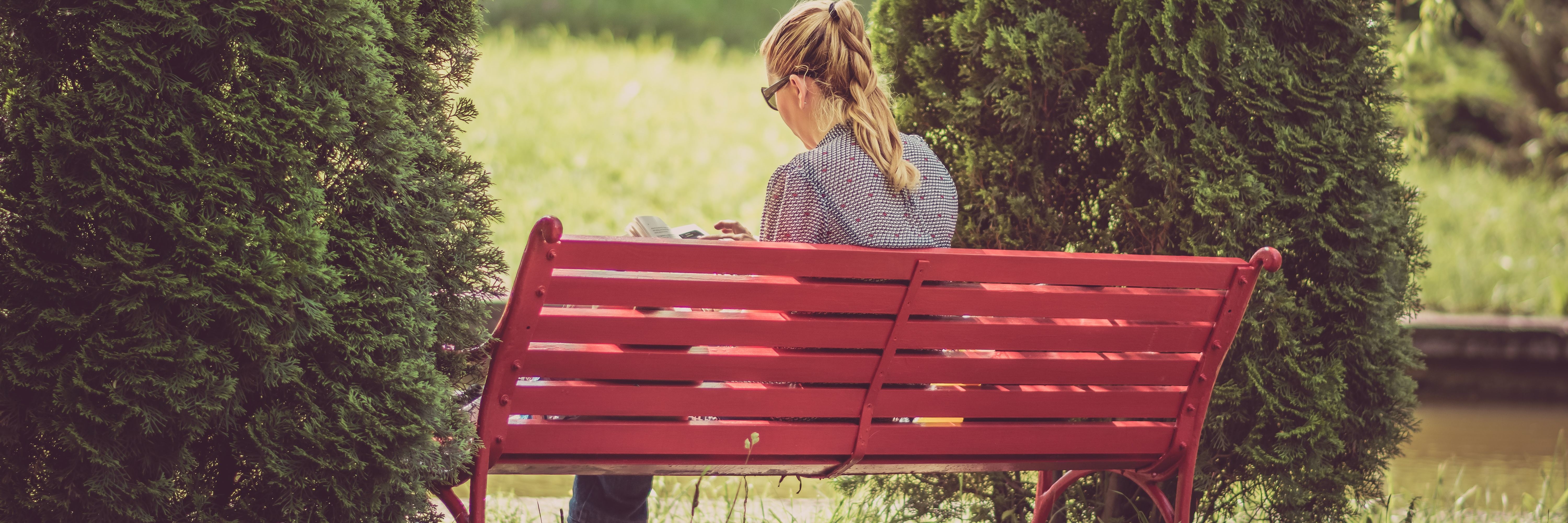 How to Practice Self-Care as a Therapist blonde woman wearing glasses reading on red bench in nature