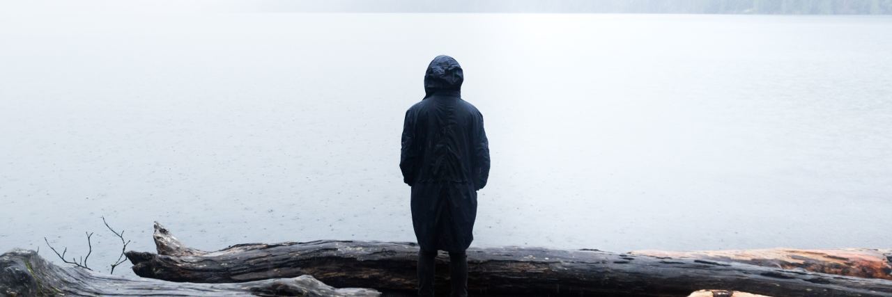 Why Health Insurance Needs to Cover Suicide Attempts a woman stands by a pond while it rains