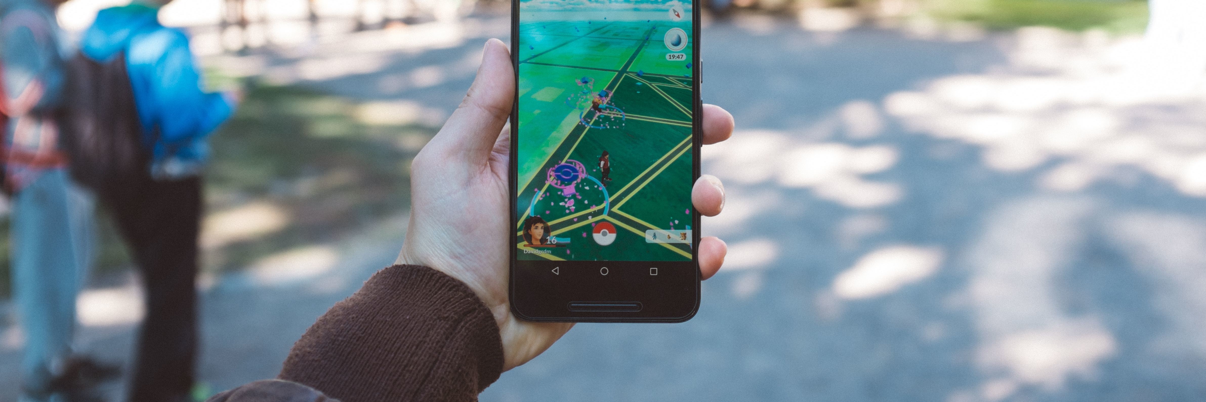 How Video Games Help With My Depression person holding phone in public playing pokemon go