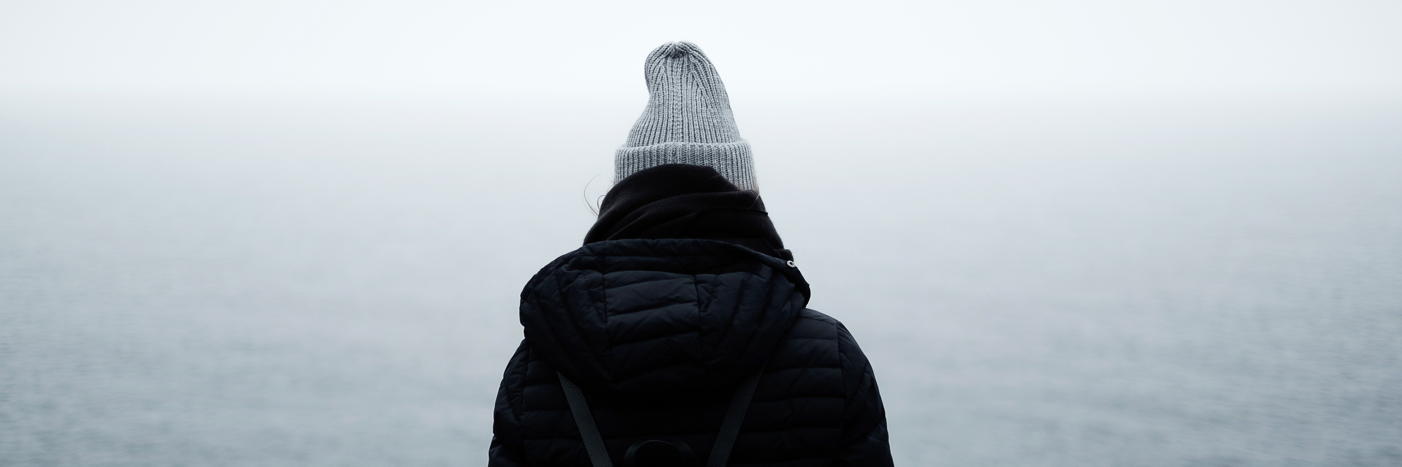 How My Mental Illness Makes Me Avoid Social Connections person looking out at misty ocean wearing hat and coat