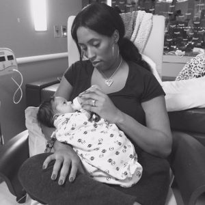 Mother holding her baby, giving her baby a bottle in a hospital room