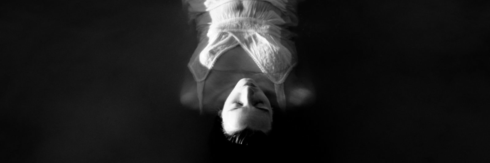 black and white photo of woman lying in ocean face upwards