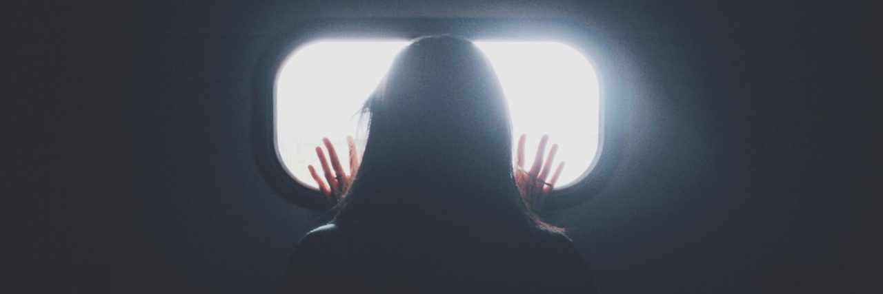 How Understanding My PTSD Triggers Helped Me Cope silhouette of woman against small bright window looking out with hands pressed against it