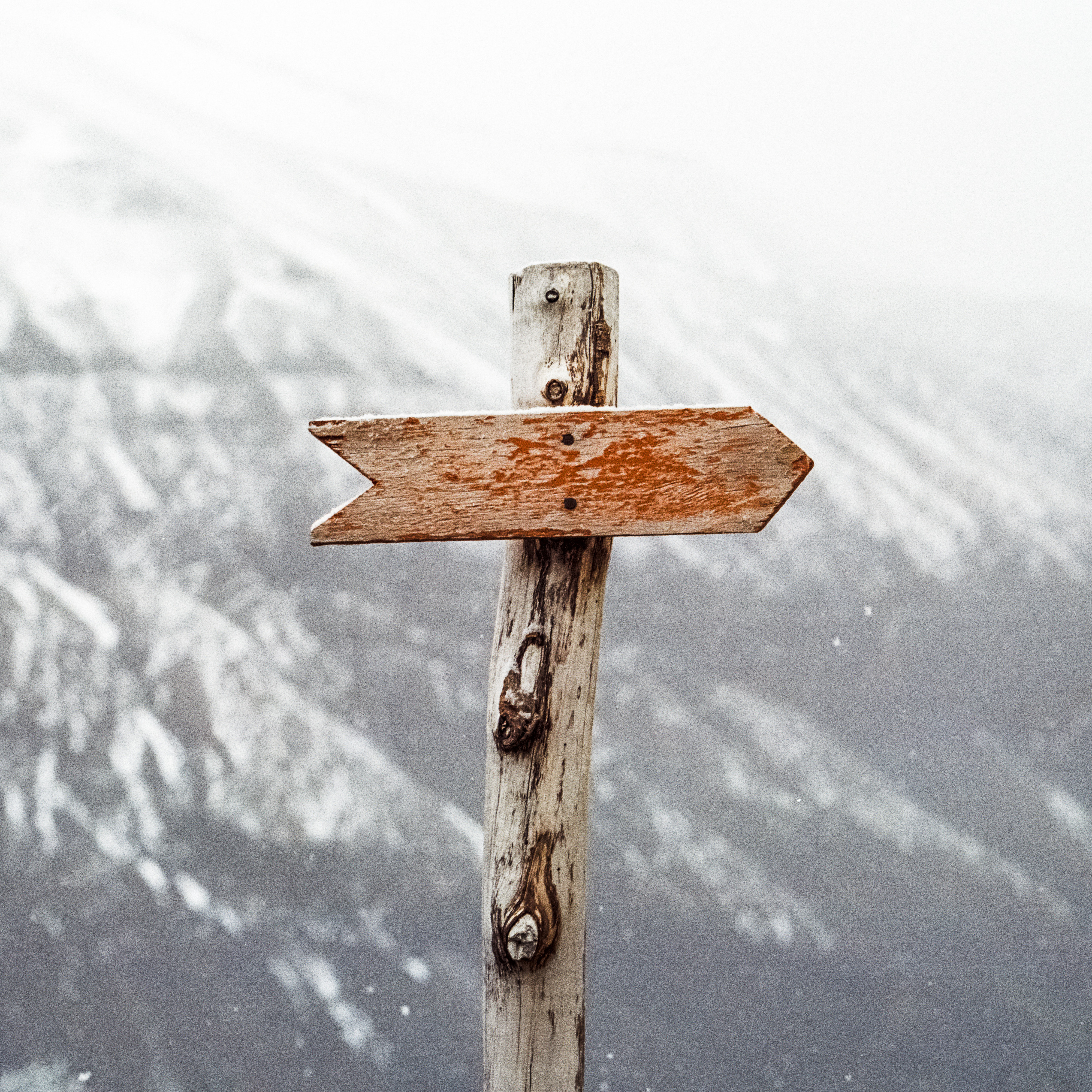 post with an arrow pointing right in front of a snowy mountain