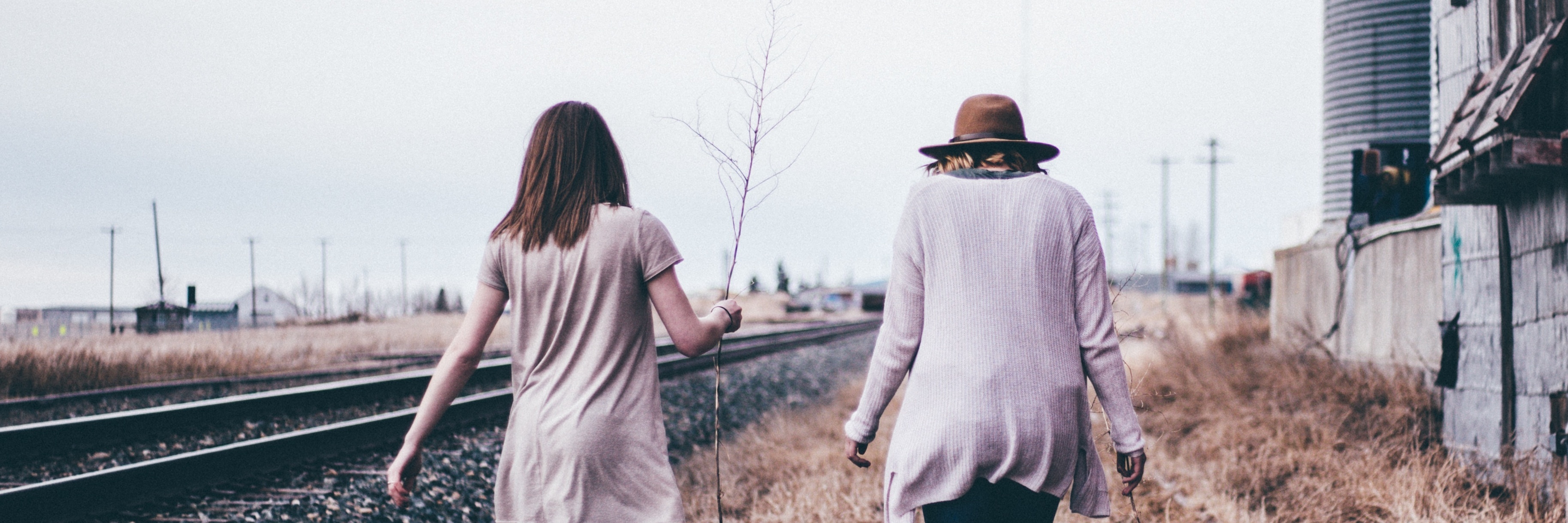 How Your Kind Words Help With My Depression and Self-Criticism two women friends walking together alongside railway track past derelict house
