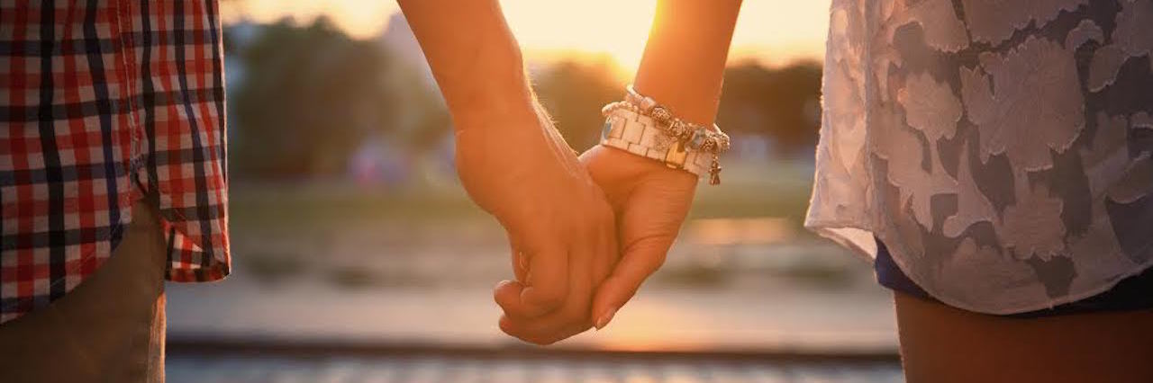 Closeup of loving couple holding hands while walking at sunset