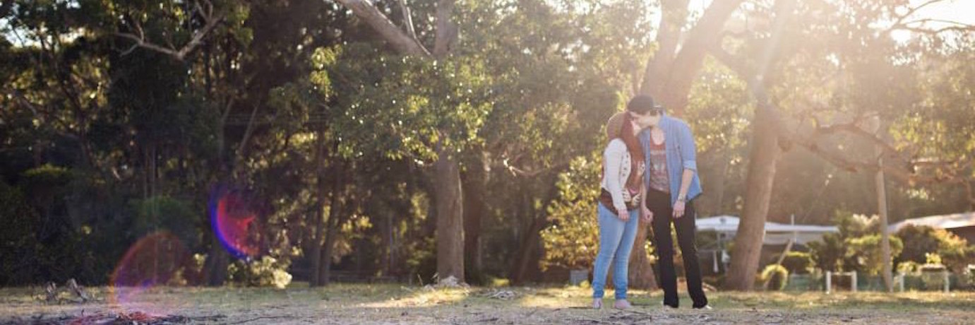 couple kissing outside in front of trees