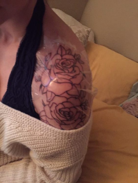 woman with rose outlines tattooed on her shoulder