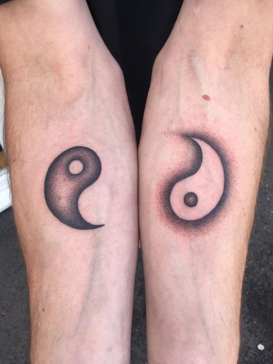 man with yin and yang symbols tattooed on his arms