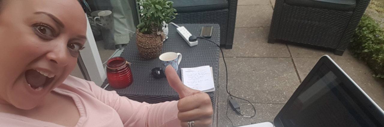 Being Positive and Accepting New Life With Chronic Illness woman smiling and giving a thumbs up next to her laptop