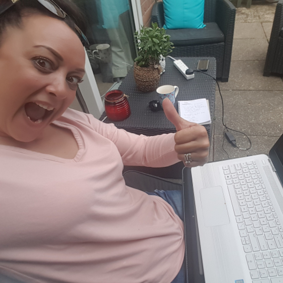 woman smiling and giving a thumbs up next to her laptop
