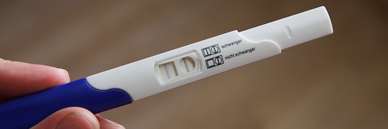 Fibromyalgia, PCOS: Getting Pregnant When You Have Chronic Illness woman holding a pregnancy test