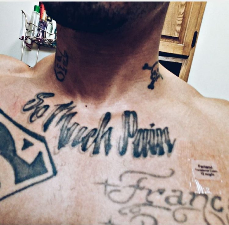 man with tattoo on his chest saying 'so much pain'