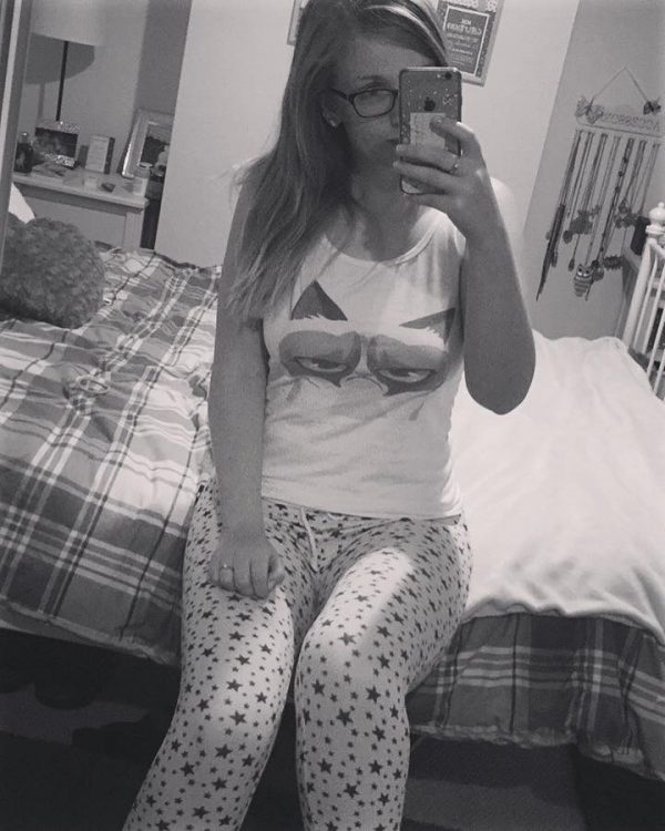black and white photo of woman in grumpy cat pajamas sitting on her bed