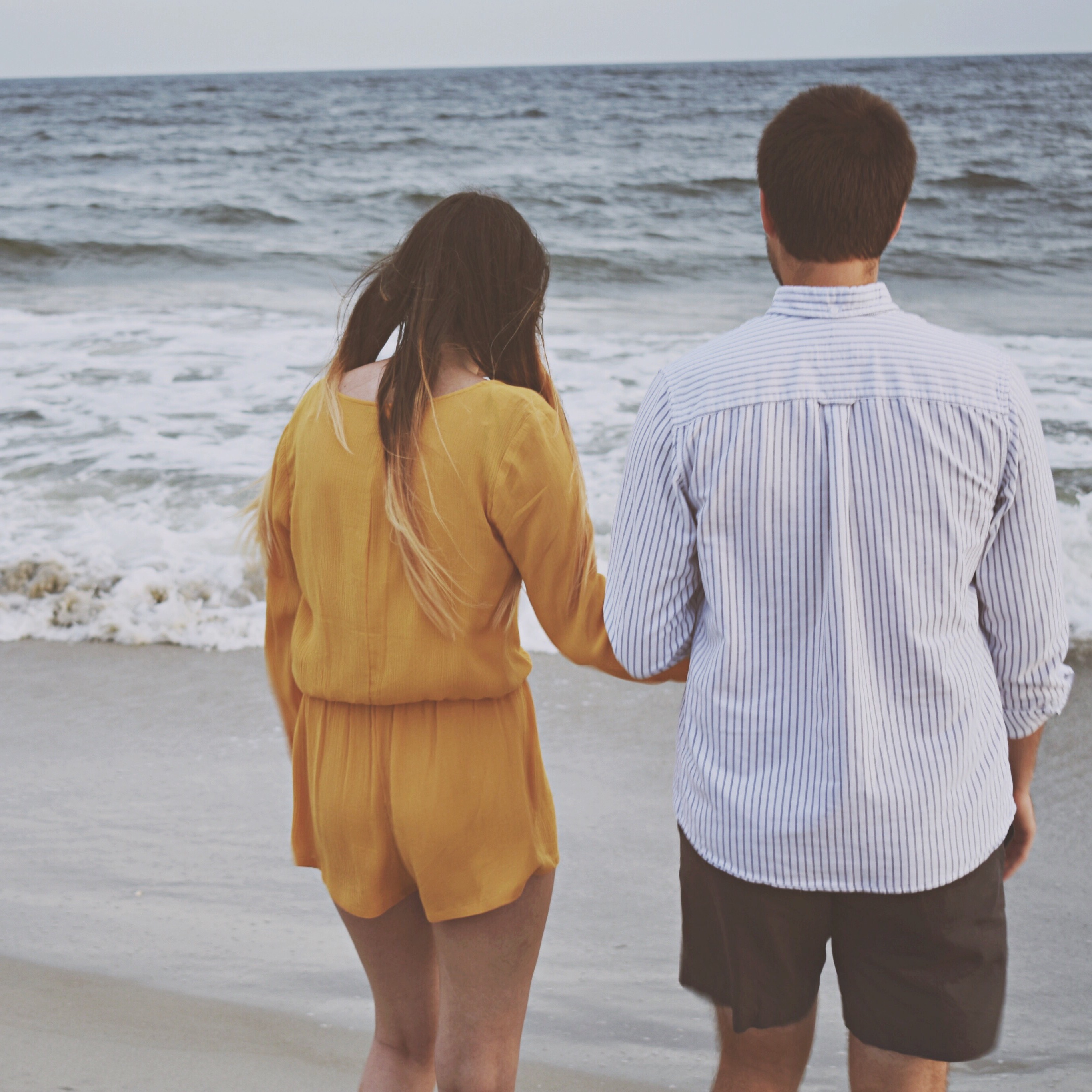 man and woman holding hands on the beach