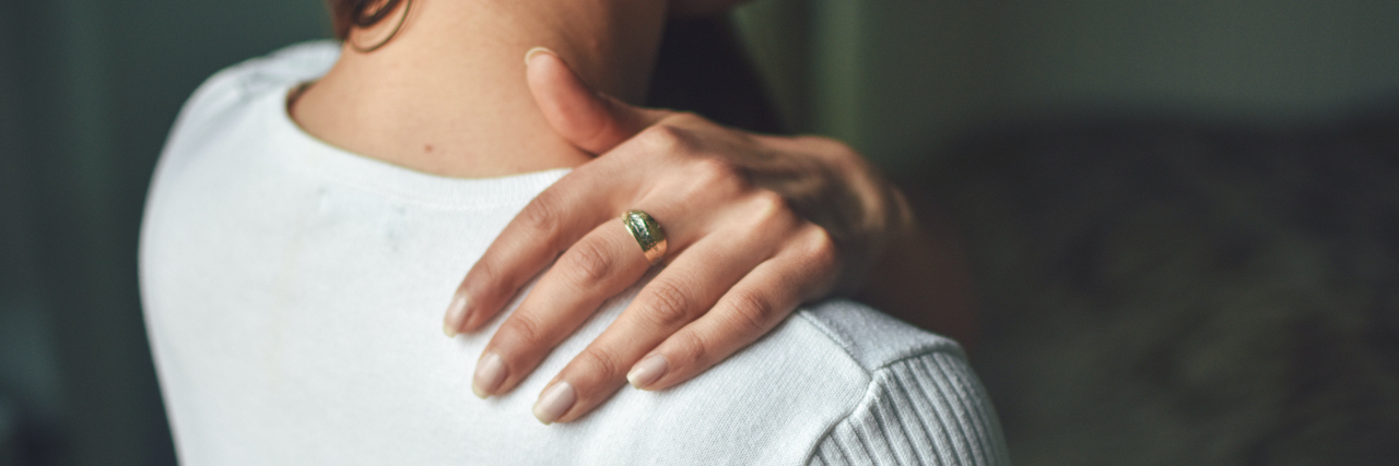 24 Surprising Physical Symptoms of Ehlers-Danlos Syndrome (EDS) Woman holding her shoulder (view from behind)