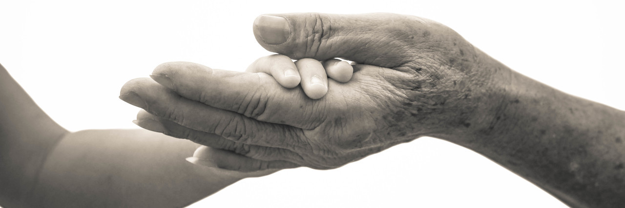 How My Son With Autism Handled My Mother’s Passing From Cancer Old female hand holding young baby hand / Love and relationship in a family