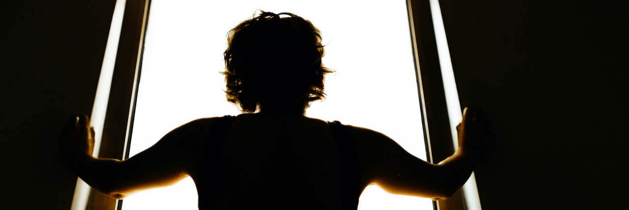 Silhouette of person looking out window