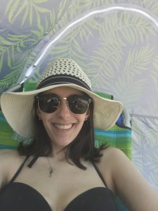 woman lying in the shade wearing a hat and sunglasses