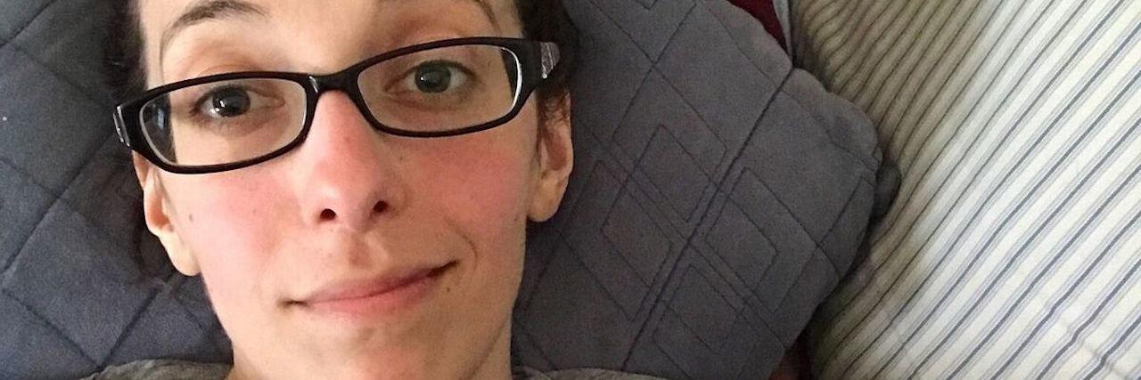 Going Through the Grieving Process Again After a Bad Lupus Flare selfie of a woman lying on her couch and wearing glasses