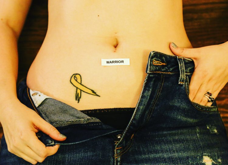 A woman shows her endometriosis tattoo, along with a sticker that reads, "Warrior."