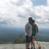 woman hiking a mountain with her husband and dog
