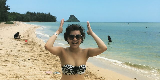 woman in a bikini standing on the beach and laughing