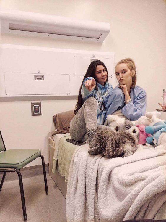 two girls on hospital bed smiling at camera