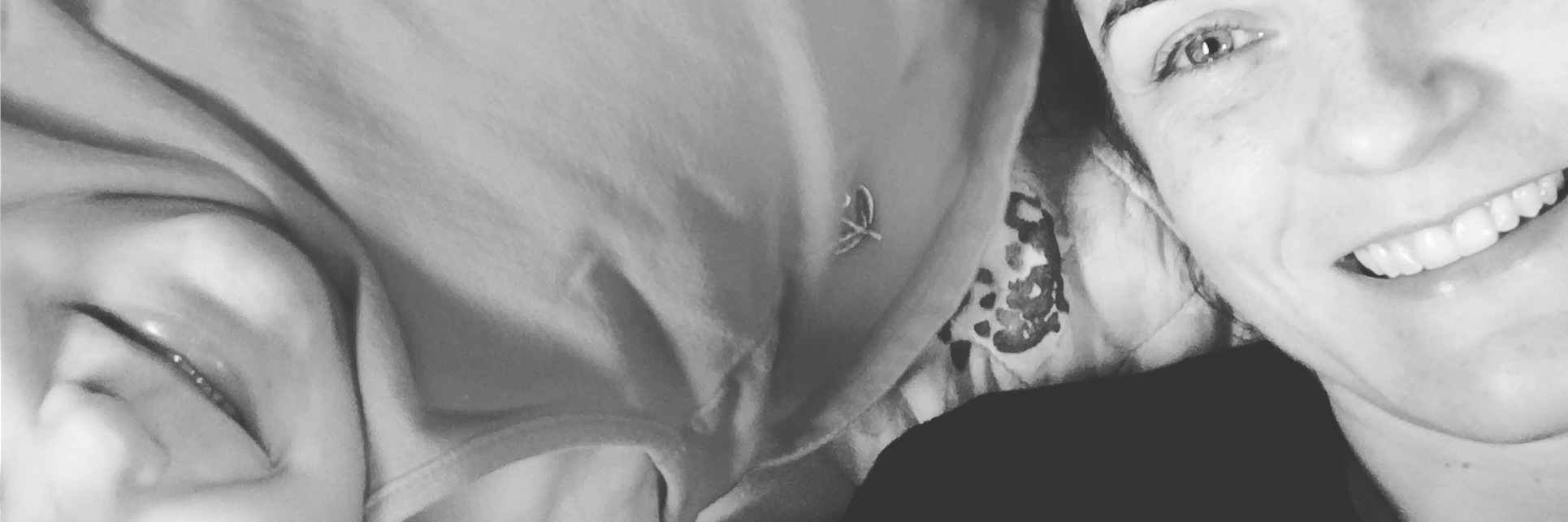 What I'd Tell Myself About Postpartum Depression After Recovery black and white photo of mother with 3-year-old baby lying down and smiling at camera