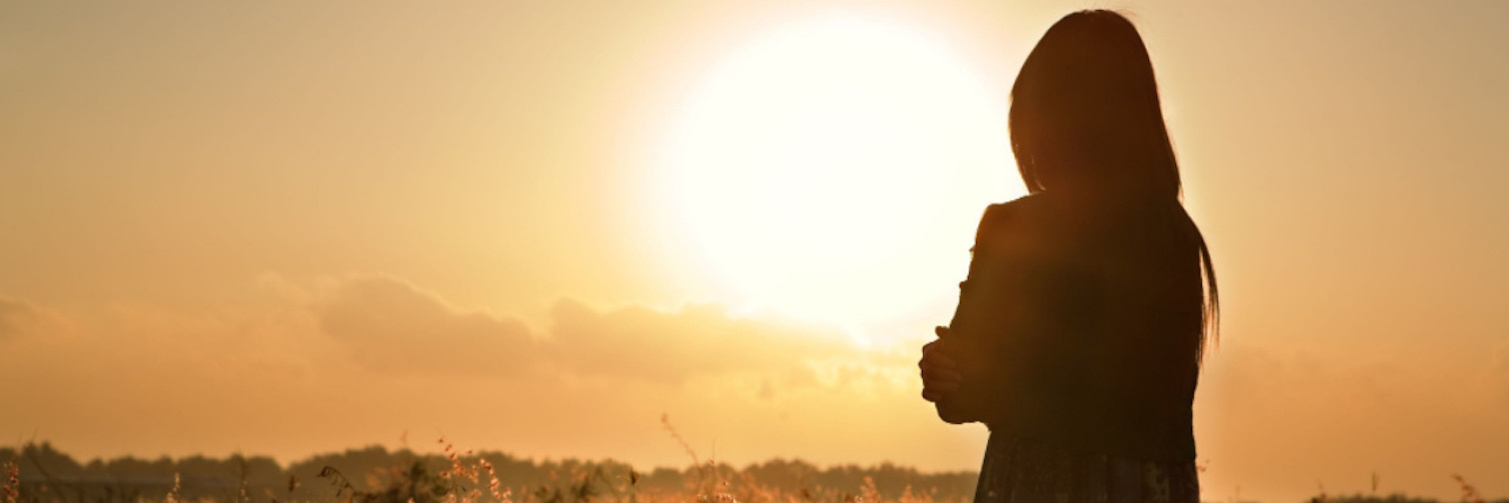 Grief: Memories of the NICU and Grieving the Loss of My Son Woman standing in field, facing sun in sky