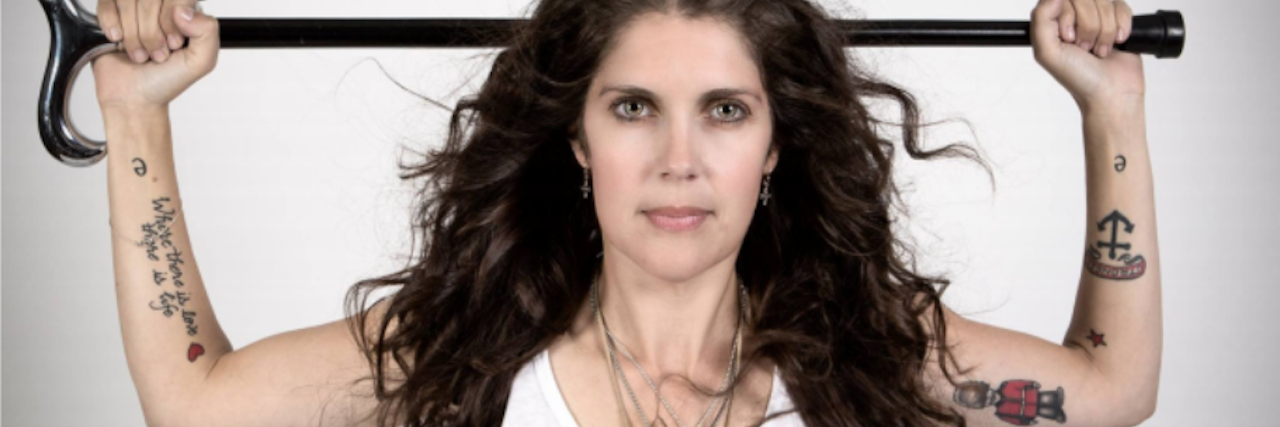 Going Through Stages of Grief With Progressive Multiple Sclerosis (MS) woman in white tank top holding a cane behind her head