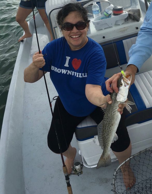 The writer holding a speckled trout in a boat.