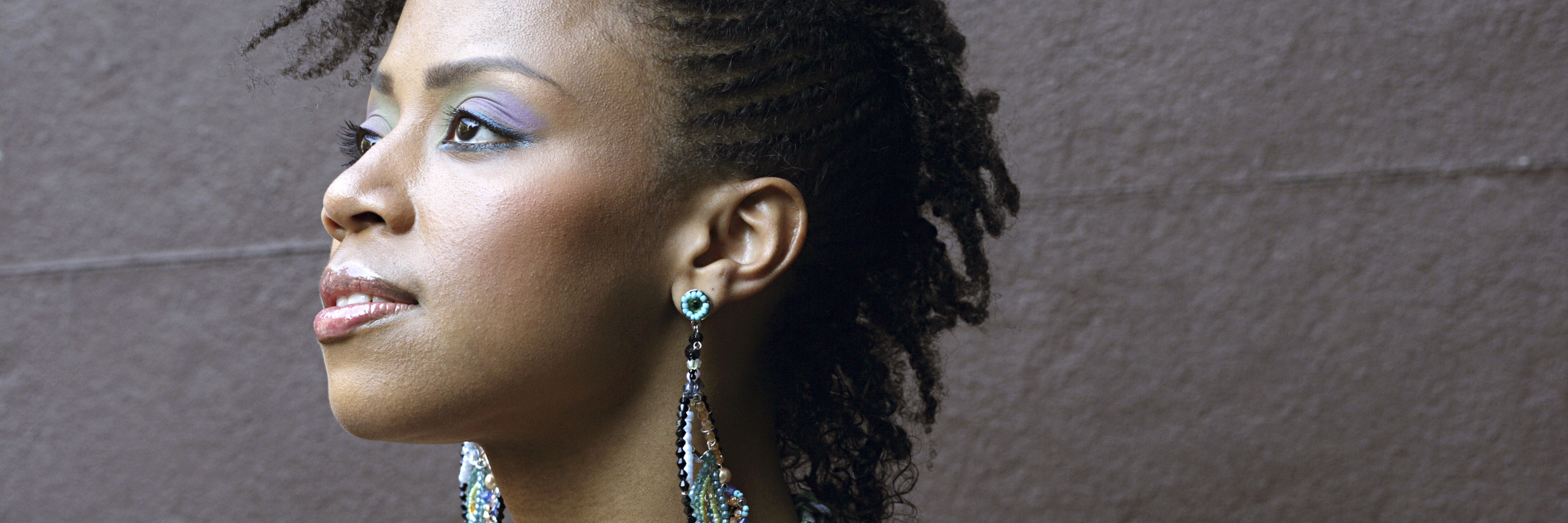 Feeling Like a Burden on Loved Ones Due to Chronic Illness portrait of a woman with colorful earrings looking off into the distance