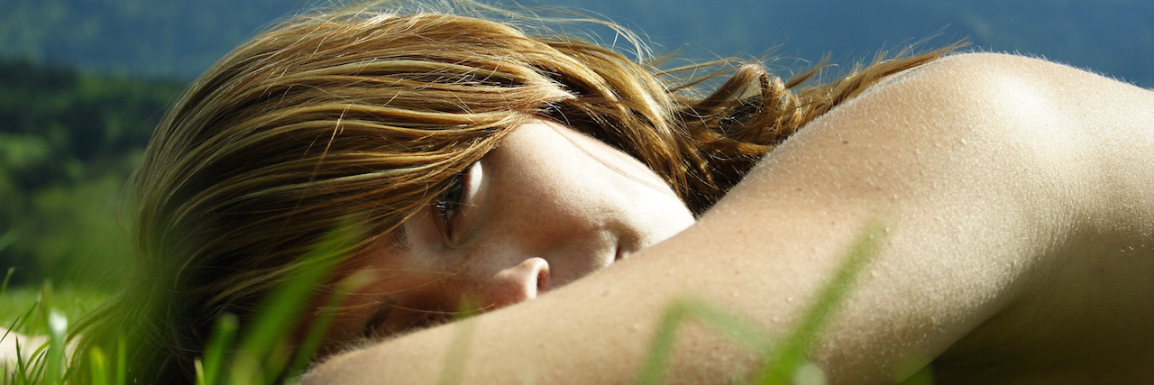 Why I Incorporate Creative Self-Care Into My Routine A woman laying down in grass