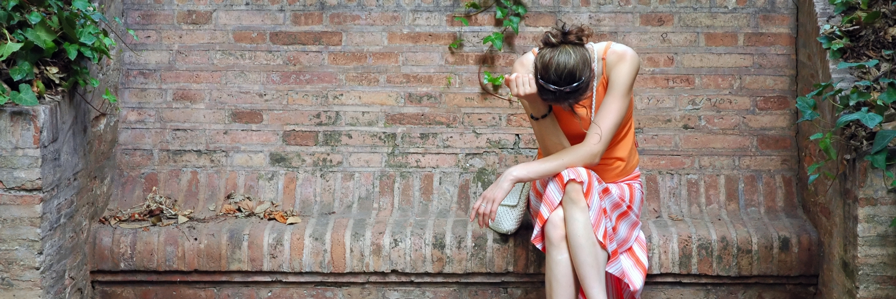 Traits Of Perfectly Hidden Depression unhappy woman in orange dress sitting on stone bench