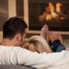 man and woman relaxing on their couch at home in front of a fireplace