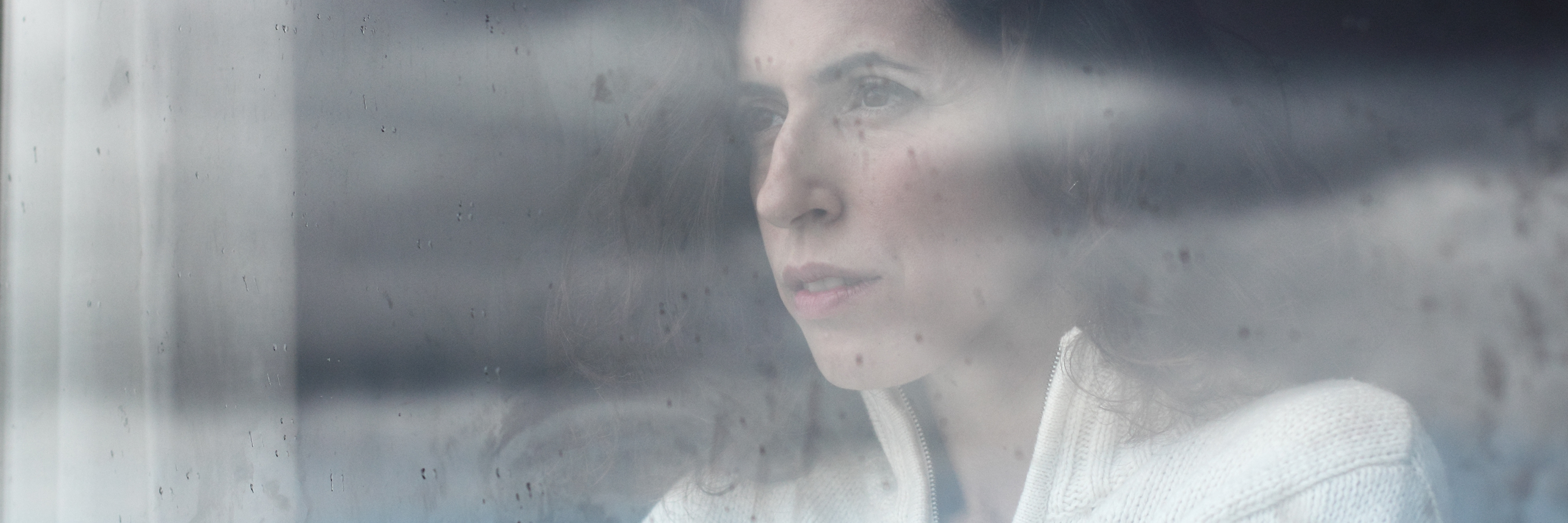Struggling With Suicidal Thoughts When You Have Chronic Pain woman looking out her window on a cloudy day