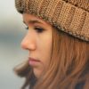 young woman wearing a hat looking sad