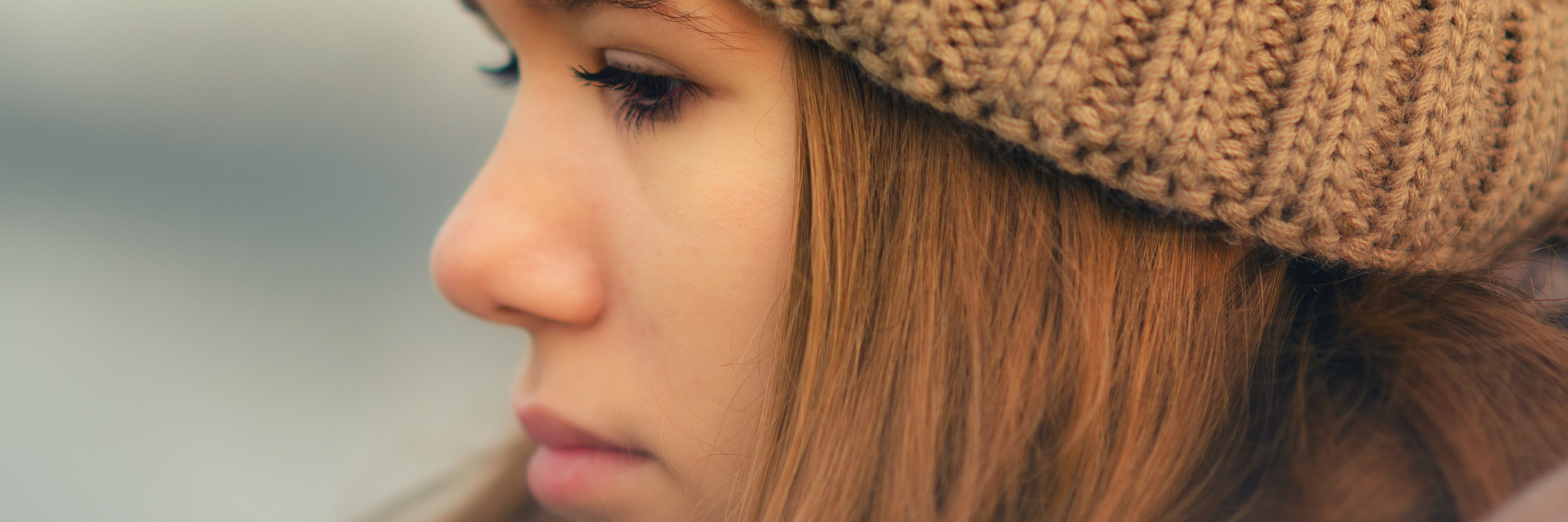 Why I Don't Tell Anyone About My Depression young woman wearing a hat looking sad