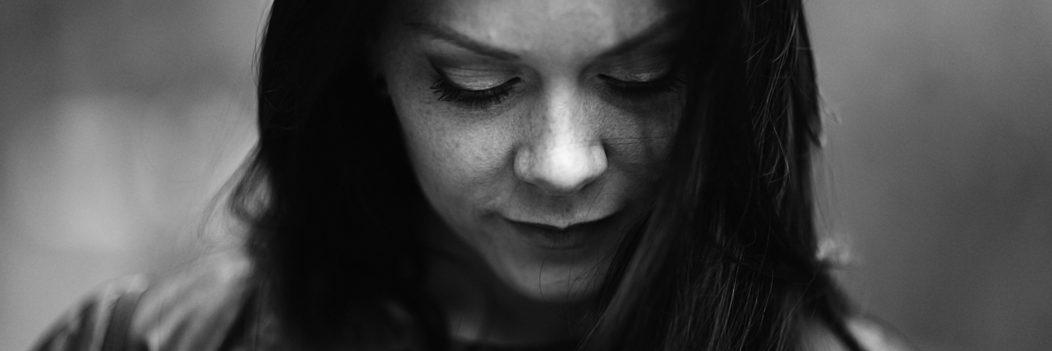 Going Through the Stages of Grieving the Loss of a Loved One Black and white photo of woman walking with eyes toward ground