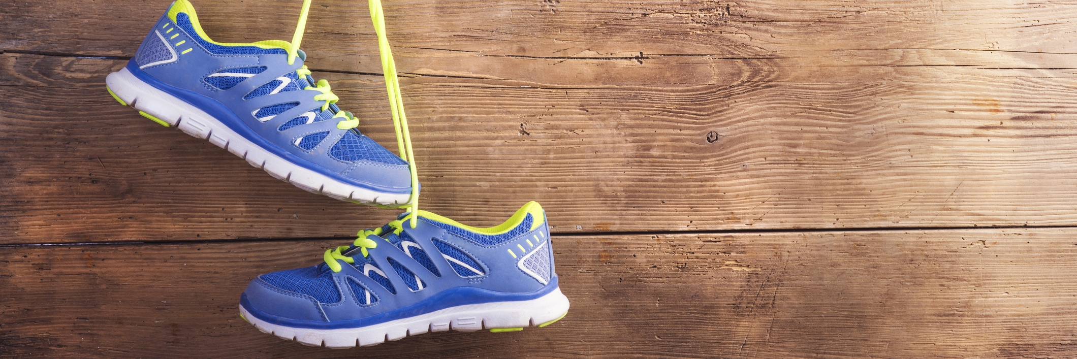 Pair of sneakers hang on a nail on a wooden fence background